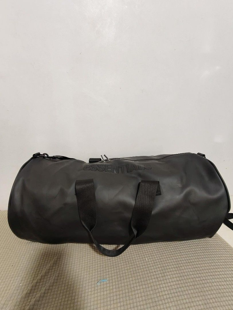 Essentials Duffle Bag (Category: Sling Bags) located in Lucena. Submitted by jmjm31 (Listing ID 1415639728, Image 1). Description: - Black duffle bag with Essentials logo. - Embossed logo on front. - Top zipper closure. - Dual handles and detachable shoulder strap. - Black fabric interior. - Essentials logo tag inside. - Ideal for travel and gym..