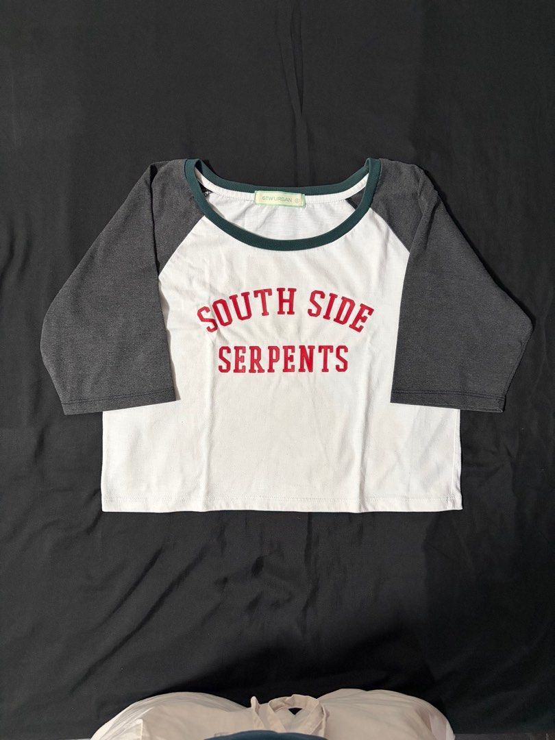 South Side Serpents Raglan T-shirt (Category: Tshirts & Polo Shirts ) located in Makati City. Submitted by prelovedump19 (Listing ID 1415790004, Image 1). Description: Cropped raglan t-shirt with "South Side Serpents" graphic. Features red text on a white body, dark gray sleeves, and green neckline trim. Casual and stylish..