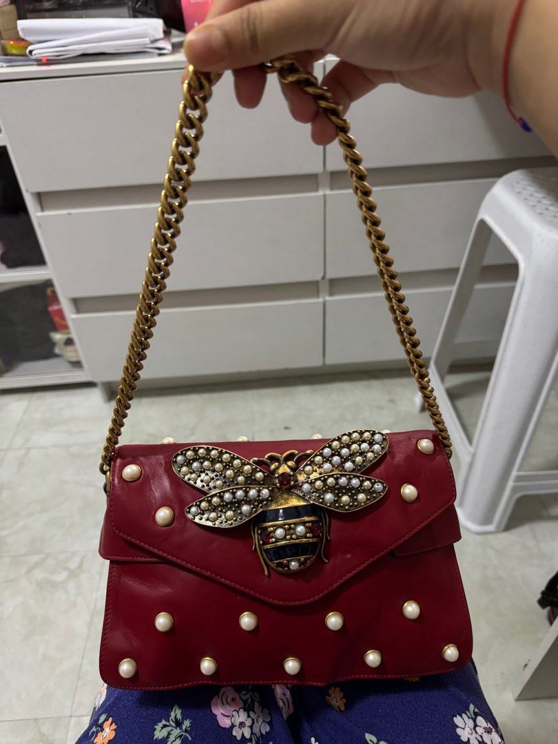 AUTHENTIC Gucci Broadway Chain Shoulder Handbag (Category: Luxury Bags & Wallets) located in Quezon City. Submitted by onestock2024 (Listing ID 1415973007, Image 1). Description: Authentic Gucci Broadway Chain Shoulder Handbag in red leather. Features a bee embellishment with pearls and a chain strap. The bag has pearl studs on the front and back. Includes a dust bag. The interior has a leather tag with the Gucci logo. 💳Mode of Payment: Gcash, B