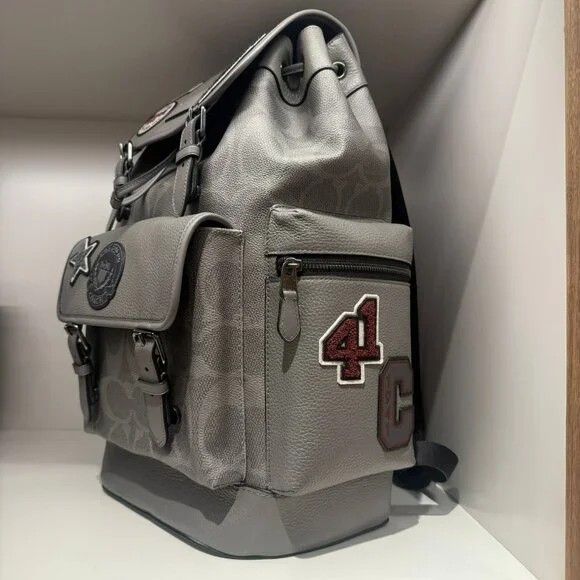 Coach Patchwork Backpack (Category: Luxury Bags & Wallets) located in Manila. Submitted by santosrich_419 (Listing ID 1415872672, Image 3). Description: - Stylish grey Coach backpack - Features multiple patches - Drawstring closure with buckle straps - Multiple pockets for storage - Coach logo pattern - Padded back for comfort - Top handle - Adjustable shoulder straps - Mix of textures and embellishments.