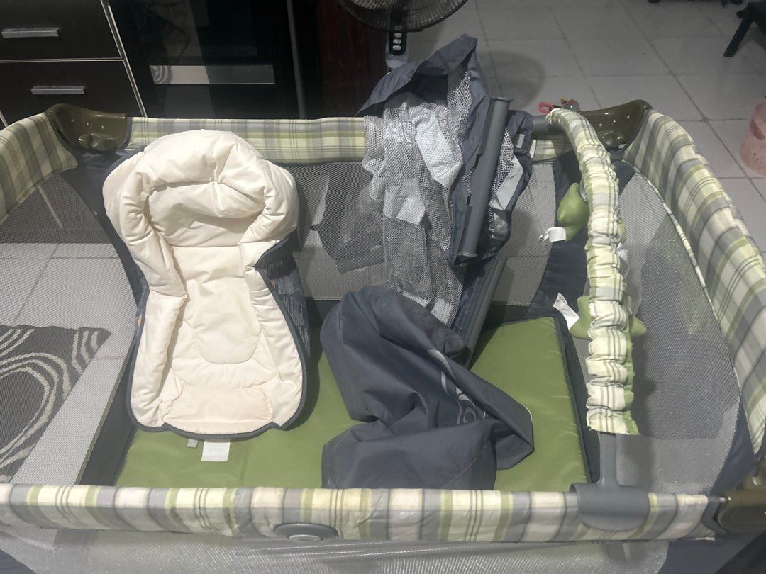 Graco Playard with Bassinet (Category: Cots & Cribs) located in San Fernando. Submitted by kimkant06043026 (Listing ID 1415823220, Image 3). Description: Graco playard with bassinet and accessories. Includes a bassinet insert, canopy with toys, and a carrying bag. The playard features a green and plaid design. The owner's manual is included..