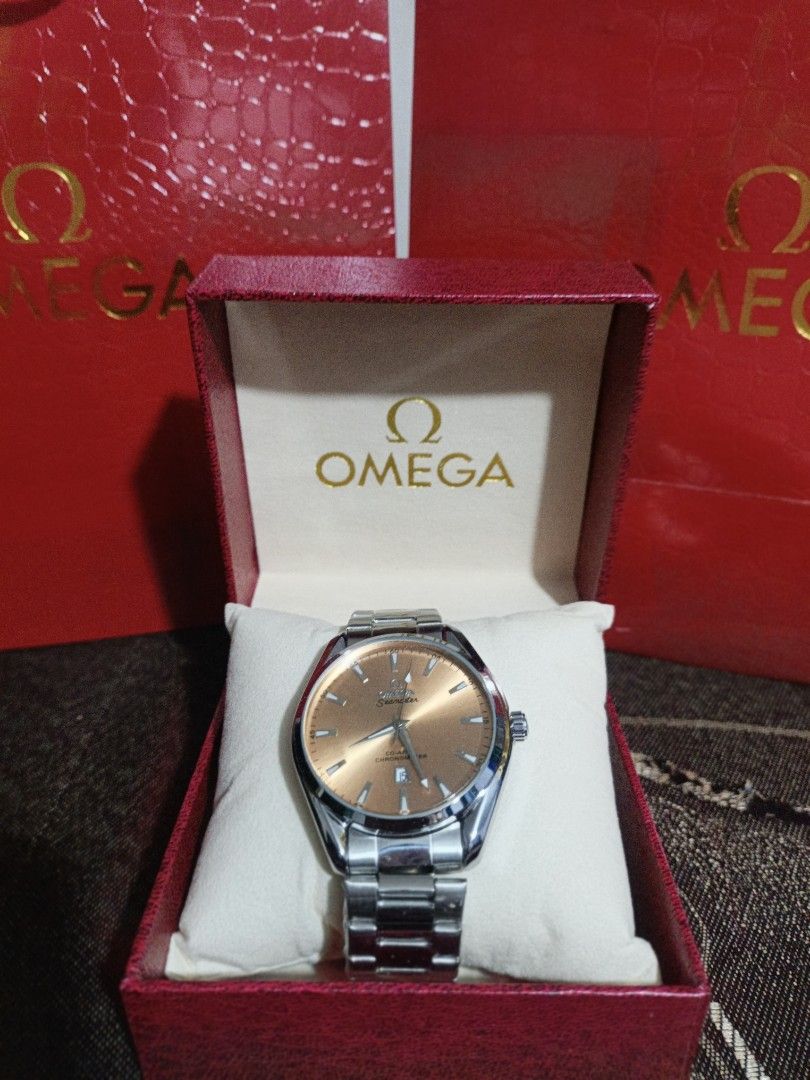 Omega Watch with Rose Gold Dial (Category: Luxury Watches) located in Meycauayan. Submitted by heronskie05 (Listing ID 1415870993, Image 1). Description: Omega watch features a rose gold dial and a stainless steel bracelet. It comes with its original box. The watch has a silver-colored case and a matching bracelet. The dial has a simple, elegant design with silver-colored hands and markers..