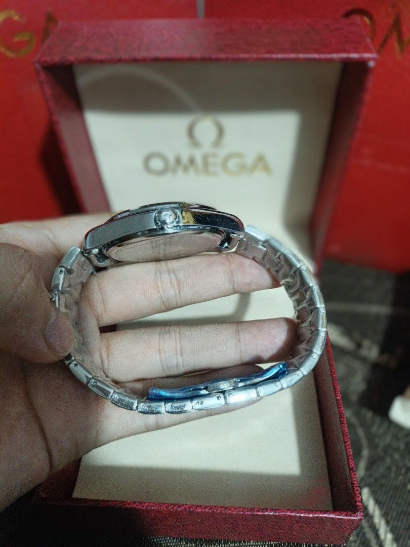 Omega Watch with Rose Gold Dial (Category: Luxury Watches) located in Meycauayan. Submitted by heronskie05 (Listing ID 1415870993, Image 2). Description: Omega watch features a rose gold dial and a stainless steel bracelet. It comes with its original box. The watch has a silver-colored case and a matching bracelet. The dial has a simple, elegant design with silver-colored hands and markers..