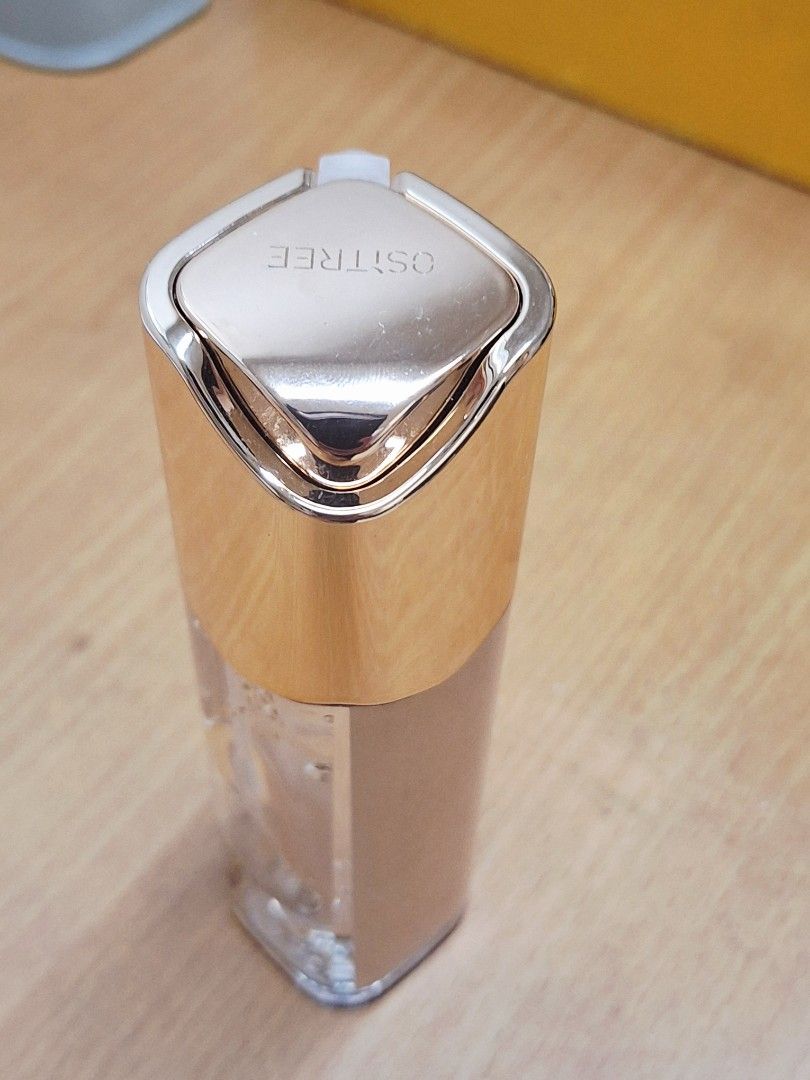 OSTREE 24K Gold Essence Liquid Foundation (Category: Makeup) located in Makati City. Submitted by rory88 (Listing ID 1415950095, Image 2). Description: - OSTREE 24K Gold Essence Foundation - Contains visible gold flakes - Features a white pump.