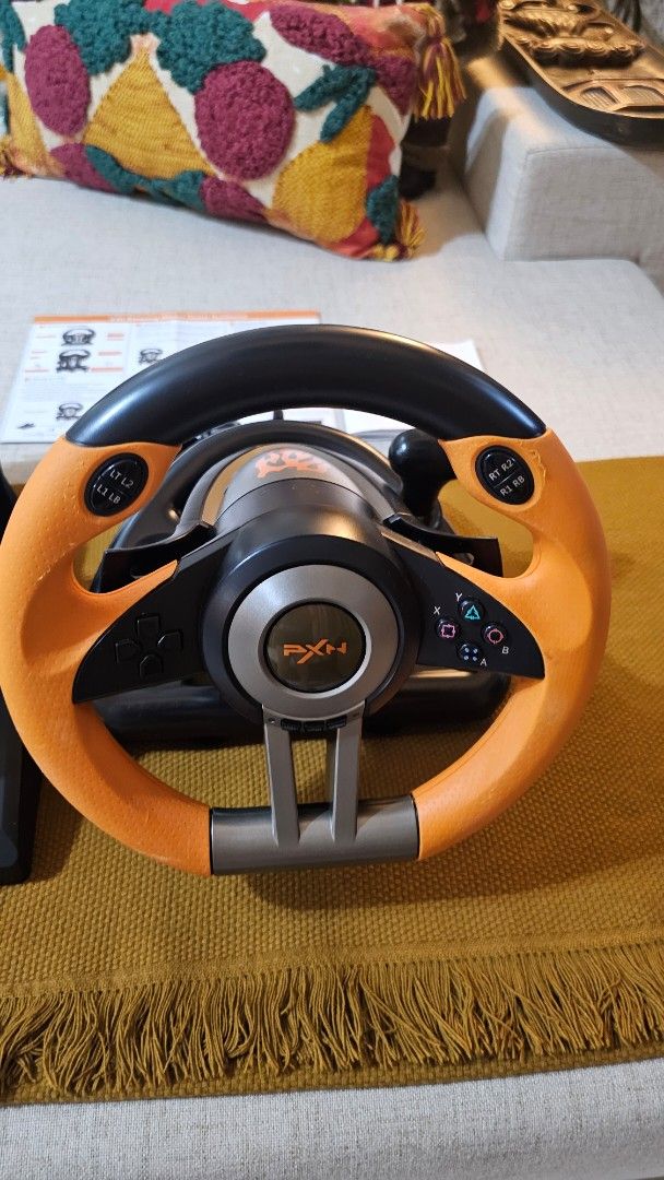 PXN V3II Gaming Steering Wheel with Pedals (Category: Controllers) located in Cebu City. Submitted by mjpashion (Listing ID 1415867862, Image 3). Description: - PXN V3II gaming steering wheel with pedals. - Stylish orange and black design. - Includes all accessories: steering wheel, pedals, and mounting hardware. - Comes with original manuals. - Perfect for enhancing your racing game experience!.