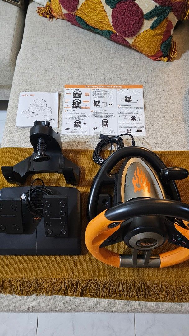 PXN V3II Gaming Steering Wheel with Pedals (Category: Controllers) located in Cebu City. Submitted by mjpashion (Listing ID 1415867862, Image 1). Description: - PXN V3II gaming steering wheel with pedals. - Stylish orange and black design. - Includes all accessories: steering wheel, pedals, and mounting hardware. - Comes with original manuals. - Perfect for enhancing your racing game experience!.