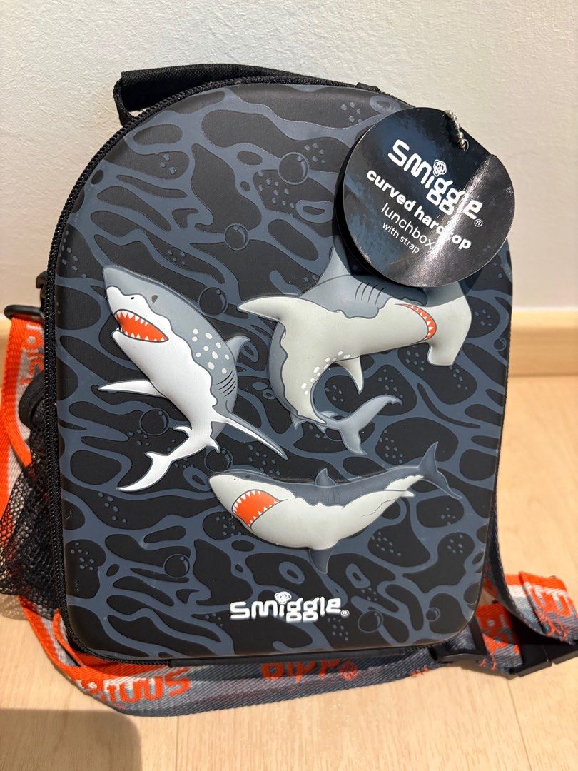 Smiggle Shark Curved Hardtop Lunchbox with Strap (Category: Babies & Kids Fashion) located in Singapore. Submitted by carrieweeeeee (Listing ID 1415978650, Image 1). Description: - Brand new Smiggle lunchbox but just needs a bit of wiping due to dust - Fun shark design - Curved hardtop - Includes a carrying strap - Separate compartment for extra storage - Ideal for school or outings .