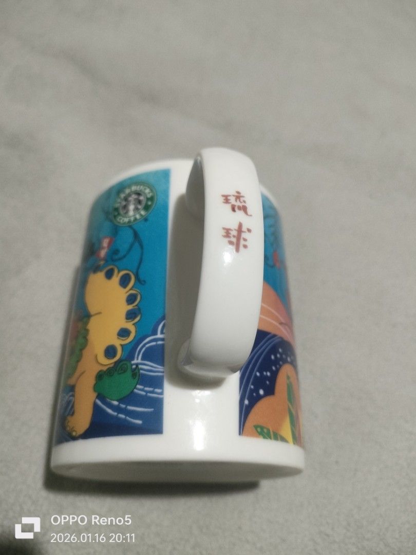Starbucks Okinawa Mug (Category: Coffee & Tea Tableware) located in Davao. Submitted by mengsmixitems (Listing ID 1415944814, Image 3). Description: - Starbucks Okinawa mug with a unique lion-dog design. - Features a white handle and interior. - Made in Japan. - Microwave and dishwasher safe. - Starbucks logo on the bottom..