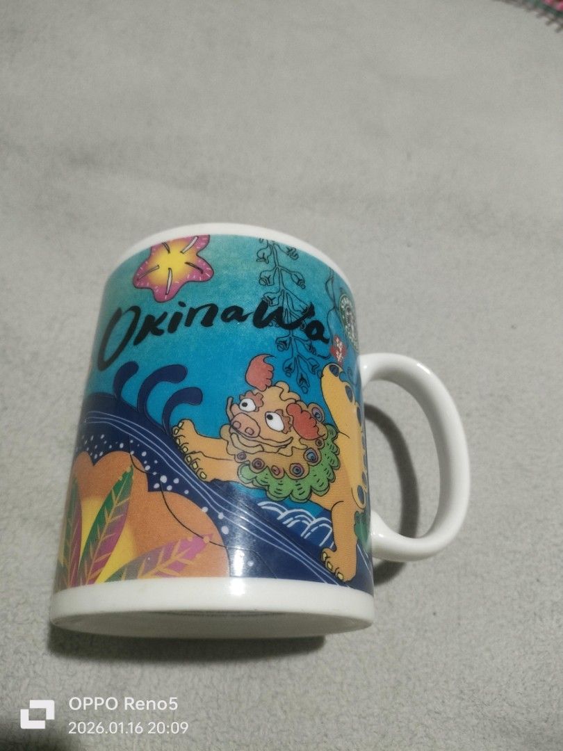 Starbucks Okinawa Mug (Category: Coffee & Tea Tableware) located in Davao. Submitted by mengsmixitems (Listing ID 1415944814, Image 1). Description: - Starbucks Okinawa mug with a unique lion-dog design. - Features a white handle and interior. - Made in Japan. - Microwave and dishwasher safe. - Starbucks logo on the bottom..