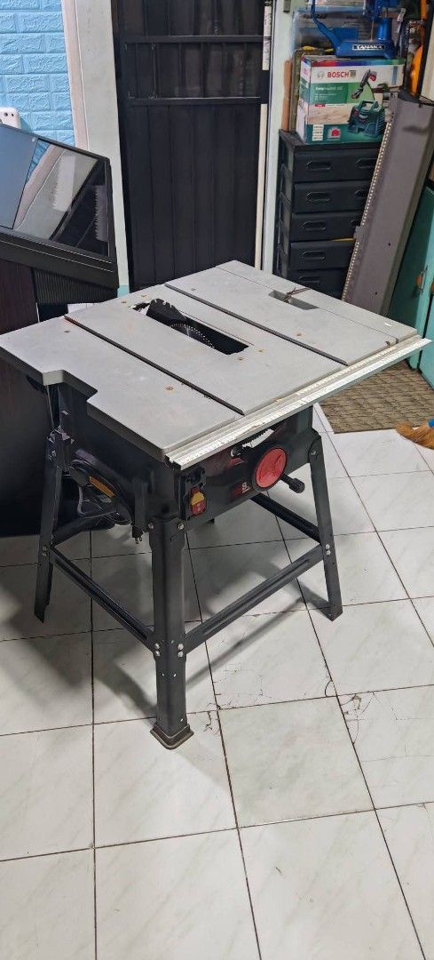 Table Saw (Category: Construction Tools & Equipment) located in Quezon City. Submitted by gwace1717 (Listing ID 1415836275, Image 1). Description: - Table saw for woodworking - Metal frame - Gray table surface - Features a blade and red adjustment knob - Mounted on a stand - Suitable for woodworking projects.