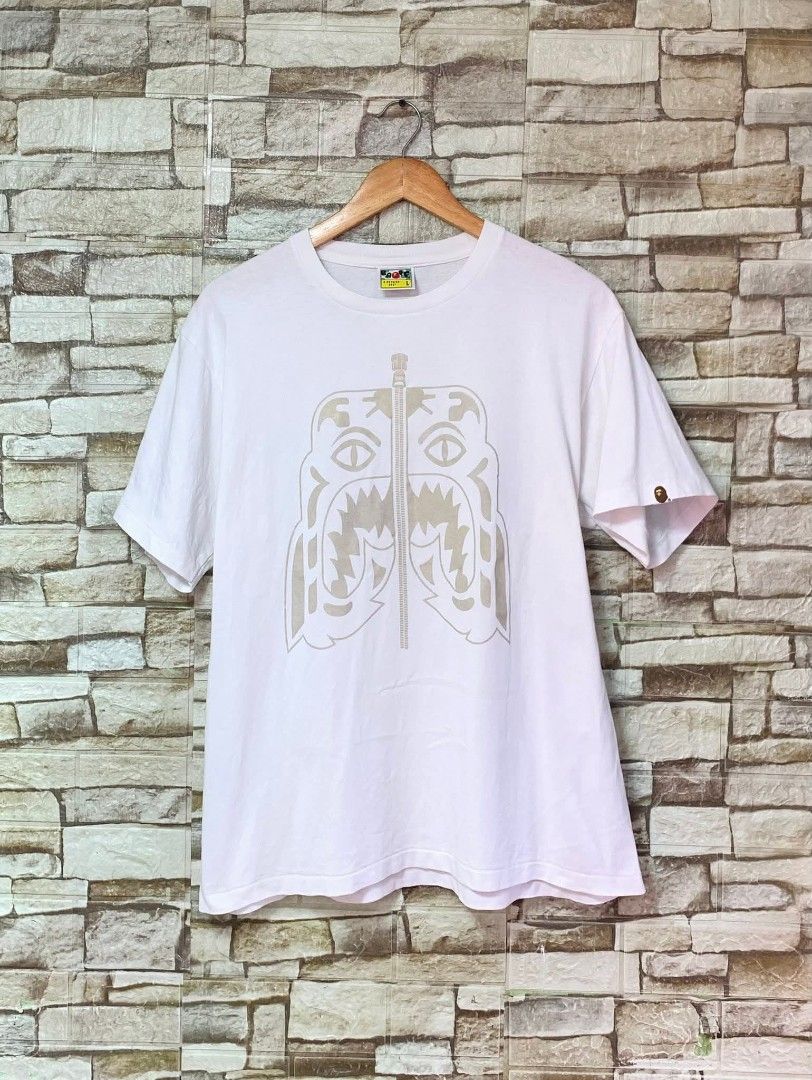 BAPE Tiger Graphic T-shirt - Large (Category: Tshirts & Polo Shirts ) located in Caloocan City. Submitted by vintstreets (Listing ID 1416174092, Image 1). Description: BAPE • Dimes: width: 21 Length: 26.5 • Condition & Color rate: 9.2/10 • no side stich • minimal hairline sa print (hindi visible) • solid din to 📥📥 📍 South Caloocan 🚚 JNT - White BAPE T-shirt - Features a tiger graphic - Crew neck and short sleeves - BAPE logo detail - Size: La