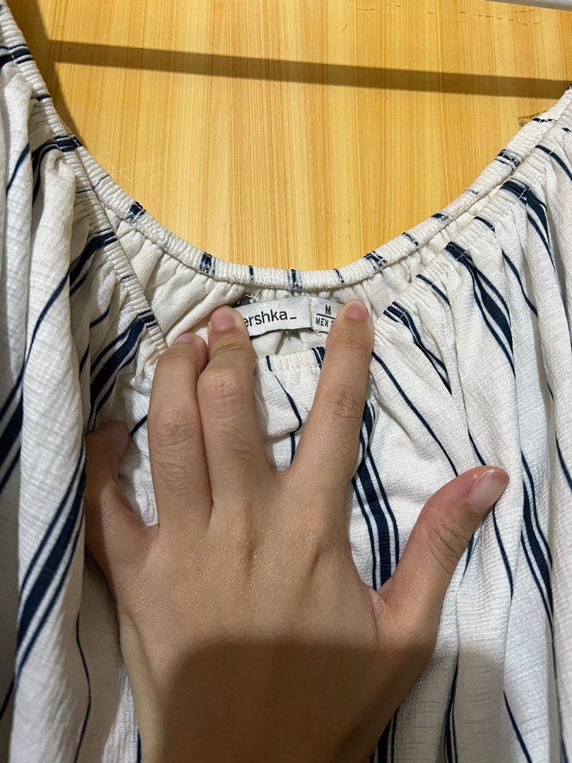 Bershka Off-Shoulder Striped Top (Category: Blouses) located in Mandaluyong City. Submitted by declutter.rs (Listing ID 1416105373, Image 2). Description: - Bershka off-shoulder top - Size: M - Color: White base with navy blue stripes - Condition: Minor yellow stains .