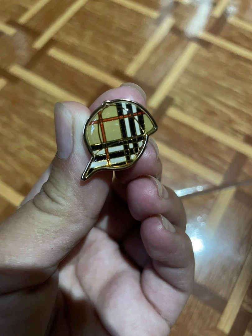 Burberry brooch/pin (Category: Luxury Accessories) located in Baguio. Submitted by cleverlion_e92944 (Listing ID 1416010096, Image 2). Description: Burberry pin features a cap design with the brand's signature check pattern. The pin has a gold-tone finish. The back of the pin is marked with the Burberry logo. It comes with a pin backing for secure attachment..