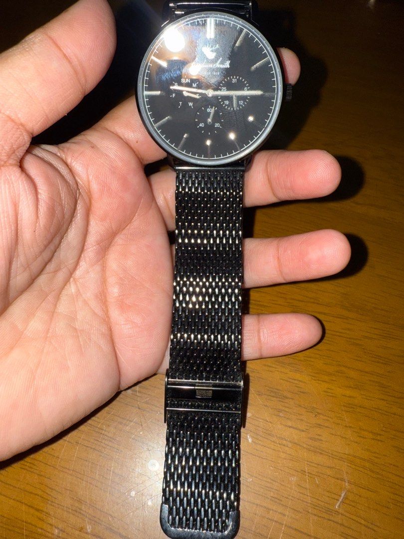 Goodwin Smith Hamilton Black Watch (Category: Luxury Watches) located in Pilar. Submitted by faveanyshop (Listing ID 1416073552, Image 3). Description: Goodwin Smith watch features a sleek black dial with subdials for day, date, and seconds. It has a black mesh strap and a stainless steel back. The watch is water-resistant up to 3 ATM. The brand's logo and the words "Since 1928" are visible on the dial. The watch is shown on a wrist in several im