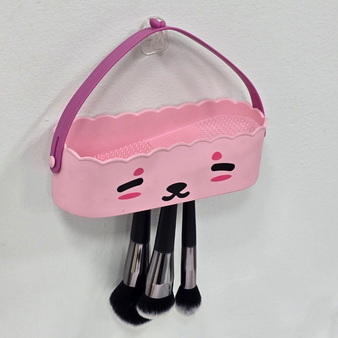 Makeup Brush Holder Cleaner (Category: Makeup) located in Marikina City. Submitted by craftedveganbrushes (Listing ID 1416037678, Image 1). Description: - Adorable pink makeup brush holder. - Features a cute cartoon face design. - Includes a convenient hanging strap. - Textured surface for easy brush cleaning. - Keeps your makeup brushes organized and accessible. - A stylish and practical accessory..