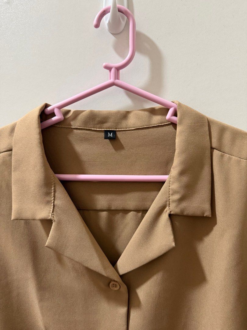 Tan Short Sleeve Button-Up Shirt - Size M (Category: Shirts) located in Quezon City. Submitted by jgcorner (Listing ID 1416069174, Image 2). Description: - Tan short-sleeved button-up shirt - Size: M - Features a collared neckline - Button-down front - Solid tan color - Lightweight material - Classic, simple design.