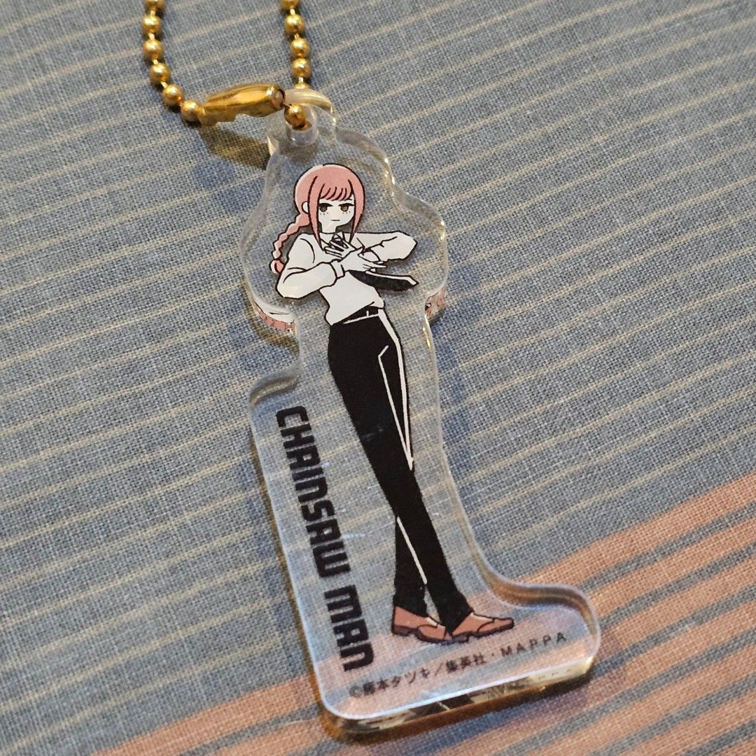 Chainsaw Man Makima Acrylic Keychain (Category: Character Goods) located in Quezon City. Submitted by chillsish (Listing ID 1416343169, Image 2). Description: - Chainsaw Man Makima acrylic keychain - Clear design - Gold-colored ball chain - Features the "Chainsaw Man" logo - Makima in a lying down pose - Japanese text on the back.