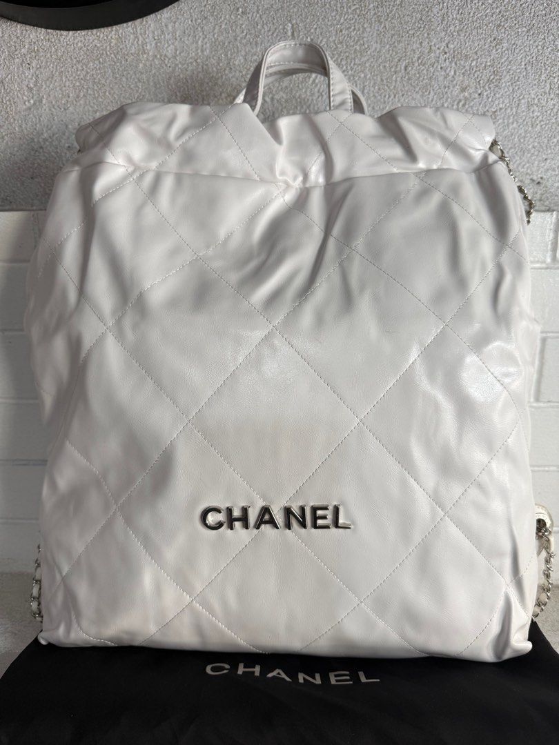 Chanel 22 Backpack White GM (Category: Luxury Bags & Wallets) located in Baguio. Submitted by drein30 (Listing ID 1416218931, Image 1). Description: White Chanel 22 backpack with diamond quilting. Features a top handle and chain straps. The interior is a light beige color with a zippered pocket and a Chanel label. The Chanel logo is visible on the front of the bag. Includes a dust bag..