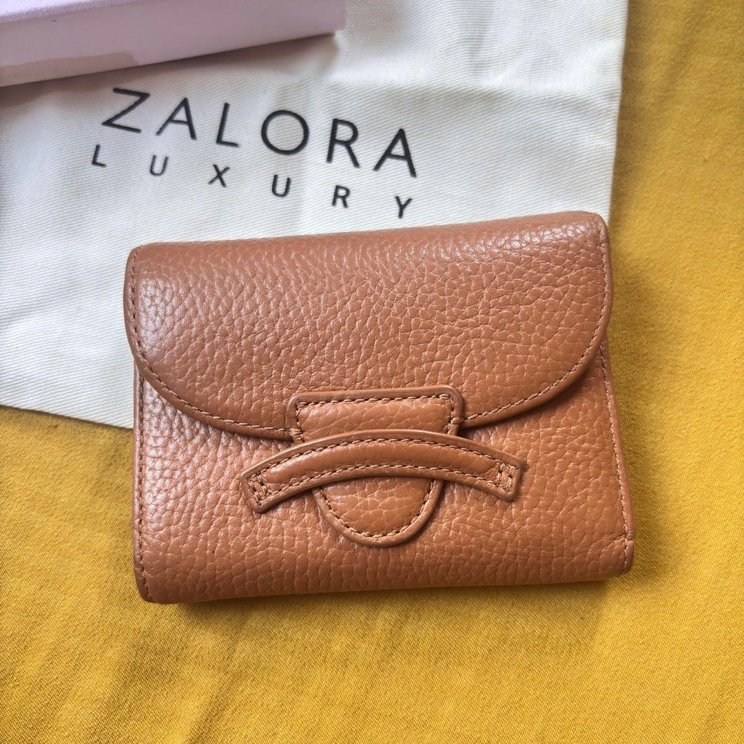 Coccinelle Small Compact Brown Leather Wallet (Category: Luxury Bags & Wallets) located in Balanga. Submitted by heyyletsdeclutter (Listing ID 1416275028, Image 1). Description: Coccinelle leather wallet in a warm brown color. Features a magnetic flap closure with a unique design. Includes a coin purse and multiple card slots. Comes with its original box and dust bag from Zalora Luxury..