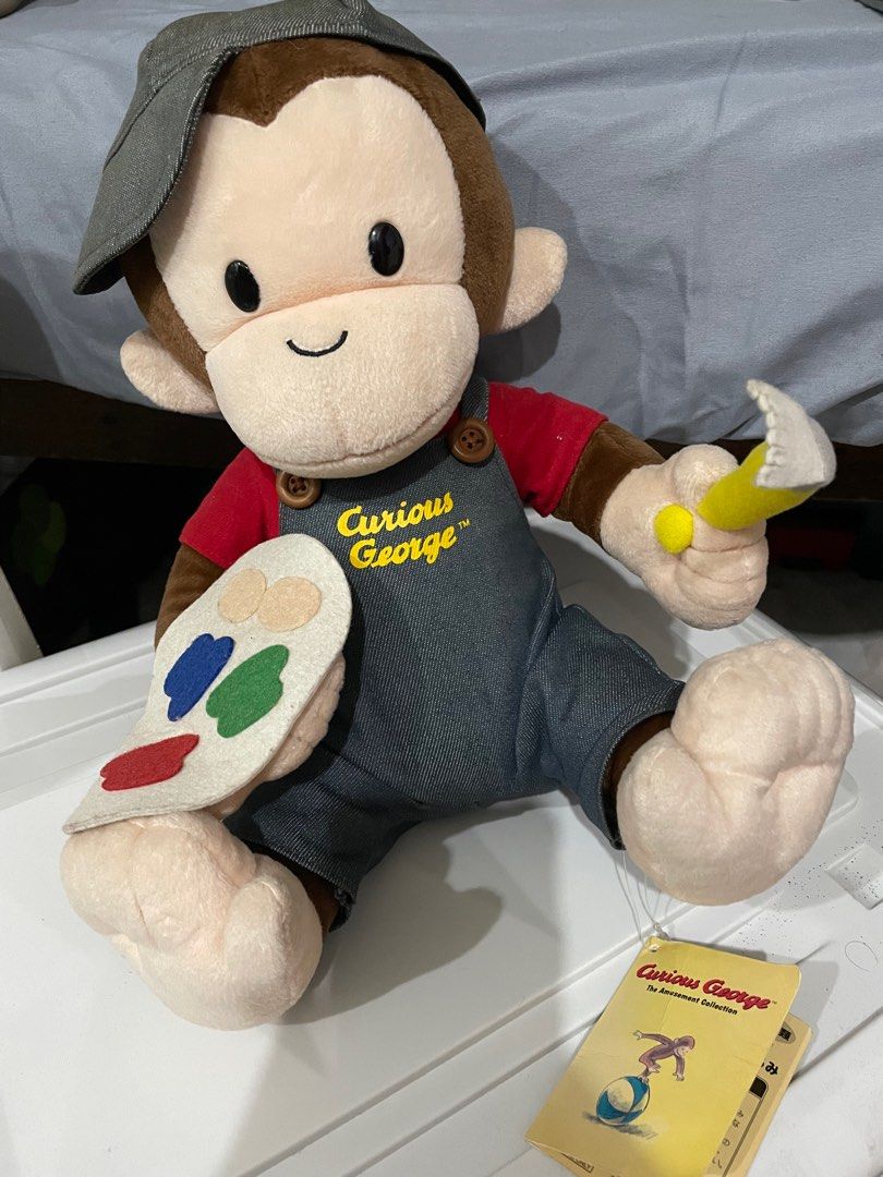 Curious George Artist Plush Toy (Category: Plushies & Soft Toys) located in Quezon City. Submitted by Aprelovedshop (Listing ID 1416279136, Image 1). Description: - Curious George plush toy dressed as an artist. - Includes a hat, overalls, and a paintbrush. - Features a colorful paint palette. - Showcases the "Curious George" logo on the overalls. - Comes with a tag from "The Amusement Collection". -with tag.