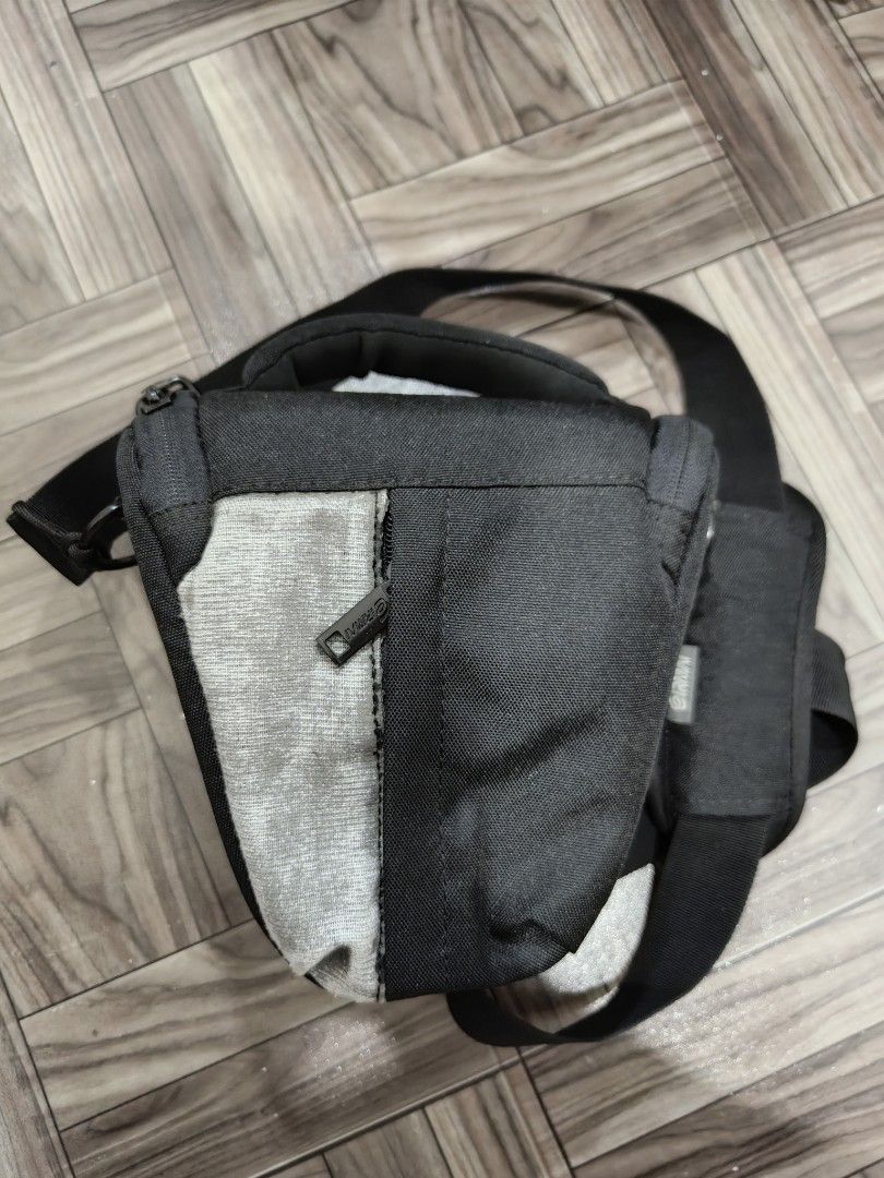 Eirmai Camera Bag (Category: Camera Bags & Carriers) located in Quezon City. Submitted by thriftstershop (Listing ID 1416406370, Image 1). Description: Eirrmai camera bag features multiple compartments and pockets for organizing camera gear. It has a padded shoulder strap for comfortable carrying. The bag has a black and gray color scheme with a zipper closure. The interior includes several padded dividers and pockets. The bag has a Eirmai logo o