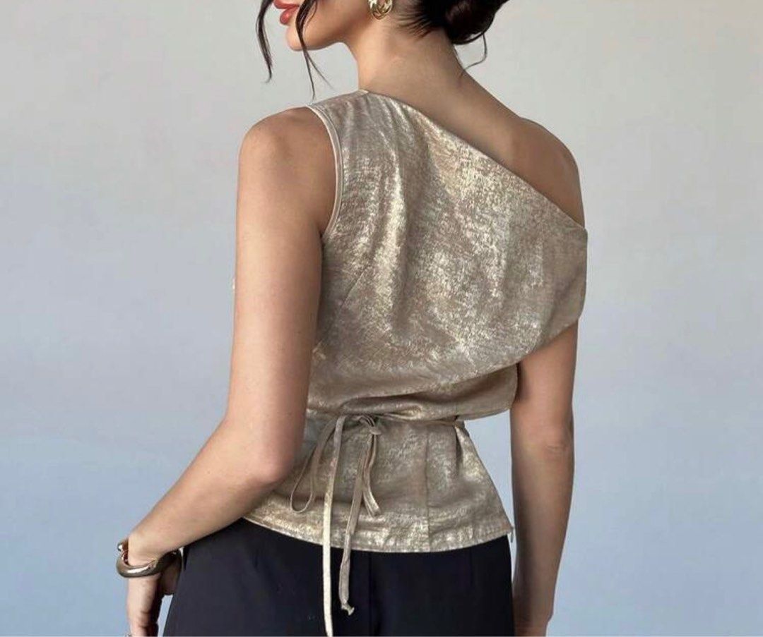 Gold One-Shoulder Top (Category: Sleeveless) located in Tanauan. Submitted by kdcstro (Listing ID 1416368677, Image 2). Description: - Worn once (christmas 2025) - Gold one-shoulder top - Draped design - Tie-back detail - Sleeveless - Asymmetrical neckline - Shimmering fabric - Ideal for special occasions.