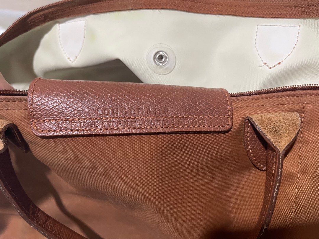 LONGCHAMP Le Pliage Green Top Handle Medium in Cognac (Category: Luxury Bags & Wallets) located in Legazpi City. Submitted by nastassjakhrystynne (Listing ID 1416336812, Image 3). Description: -Bought from Rustan’s online last July 2023 -Fair condition -Has minimal flaws: slight discoloration on the front with a pen mark, noticeable but light darkening on the back and zipper area, light yellow and blue stains in the interior, and bottom corners h
