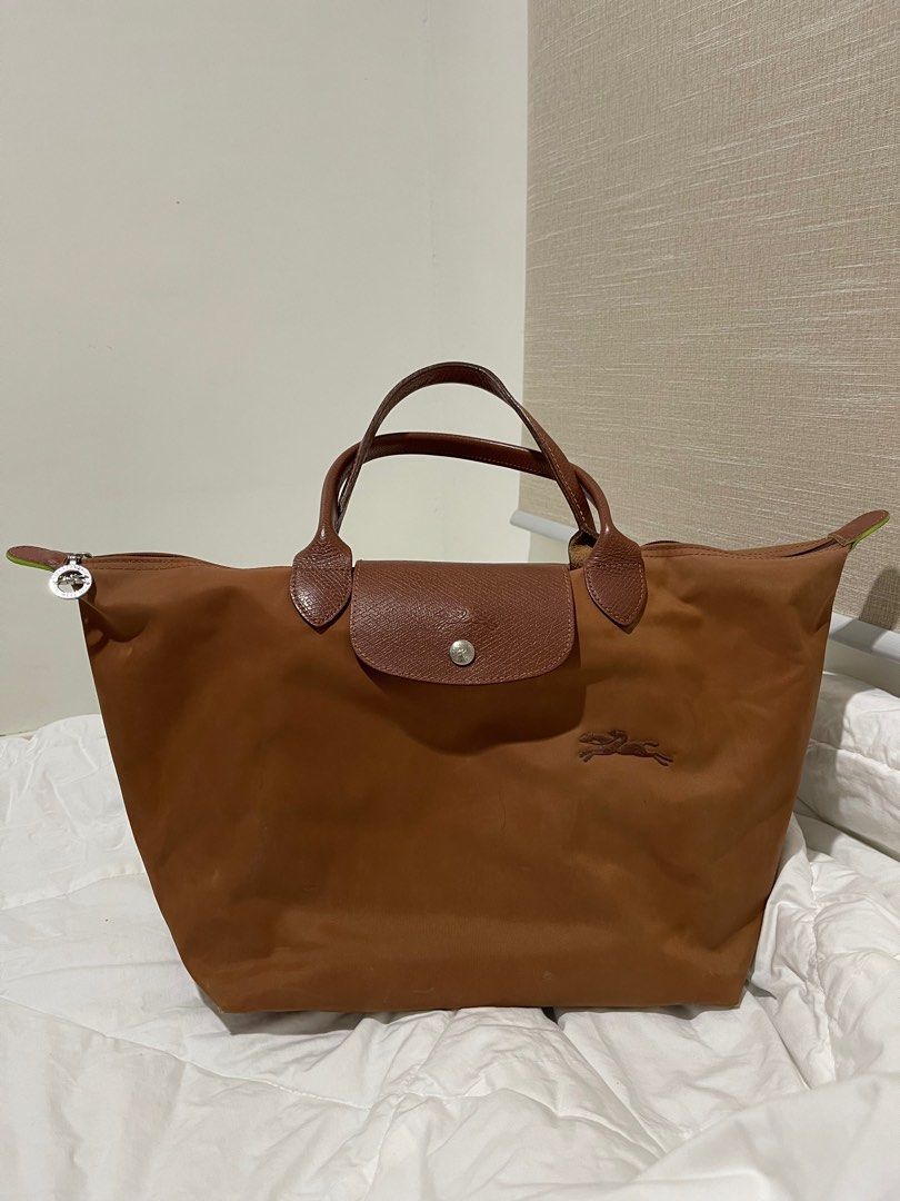 LONGCHAMP Le Pliage Green Top Handle Medium in Cognac (Category: Luxury Bags & Wallets) located in Legazpi City. Submitted by nastassjakhrystynne (Listing ID 1416336812, Image 1). Description: -Bought from Rustan’s online last July 2023 -Fair condition -Has minimal flaws: slight discoloration on the front with a pen mark, noticeable but light darkening on the back and zipper area, light yellow and blue stains in the interior, and bottom corners h
