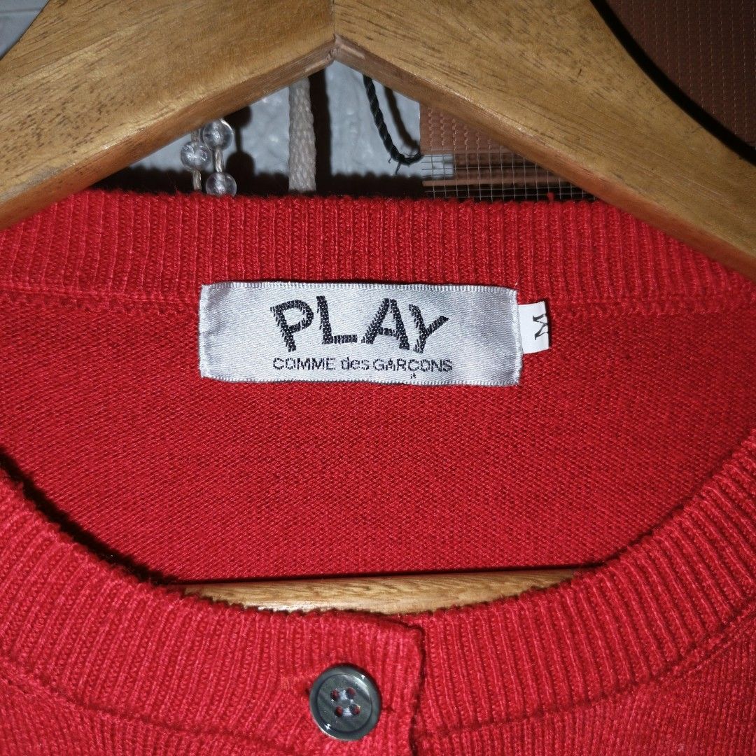 Play Comme des Garcons Red Cardigan (Category: Coats, Jackets and Outerwear) located in Goa. Submitted by kaye_dee (Listing ID 1416400240, Image 2). Description: - Play Comme des Garcons cardigan - Red color - Features black heart logo with eyes - Size M - Button-up front - Long sleeves.