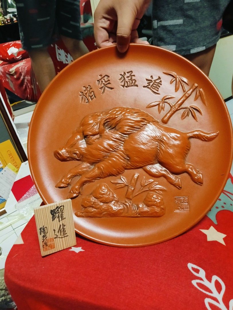 Vintage Ceramic Boar Plate (Category: Dinnerware & Cutlery) located in Manila. Submitted by josewendel71226 (Listing ID 1416416127, Image 1). Description: - Vintage ceramic plate - Features a relief of two boars with Chinese characters and bamboo accents - Reddish-brown color - Approximately 10 inches in diameter - Decorative piece - Boar relief on the back.