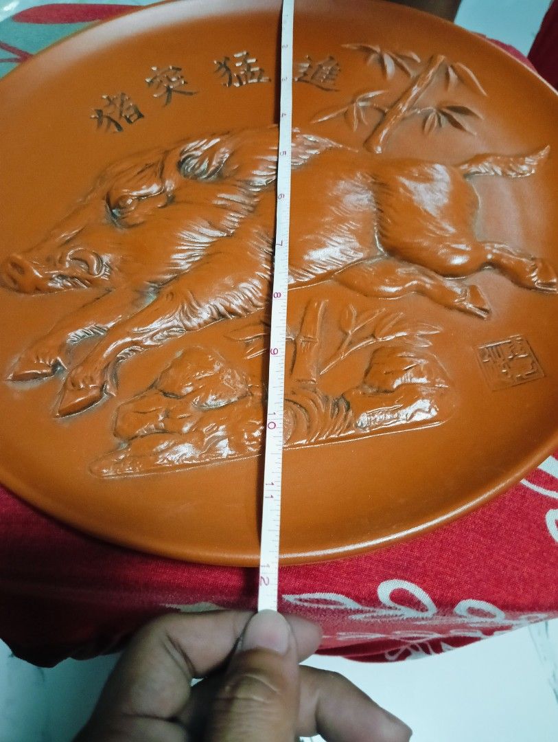 Vintage Ceramic Boar Plate (Category: Dinnerware & Cutlery) located in Manila. Submitted by josewendel71226 (Listing ID 1416416127, Image 3). Description: - Vintage ceramic plate - Features a relief of two boars with Chinese characters and bamboo accents - Reddish-brown color - Approximately 10 inches in diameter - Decorative piece - Boar relief on the back.