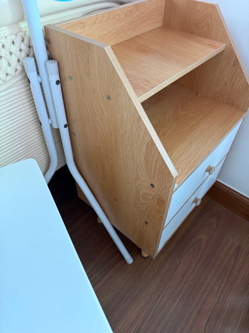 Wooden Nightstand with Drawers bedside table (Category: Shelves, Cabinets & Racks) located in Manila. Submitted by kristielyntan (Listing ID 1416313976, Image 3). Description: - Stylish wooden nightstand - Two drawers and an open shelf - Light wood finish with white drawer fronts - Unique angled design - Wooden knobs - Perfect for bedroom or living space - Adds a touch of modern design RFS: relocation.