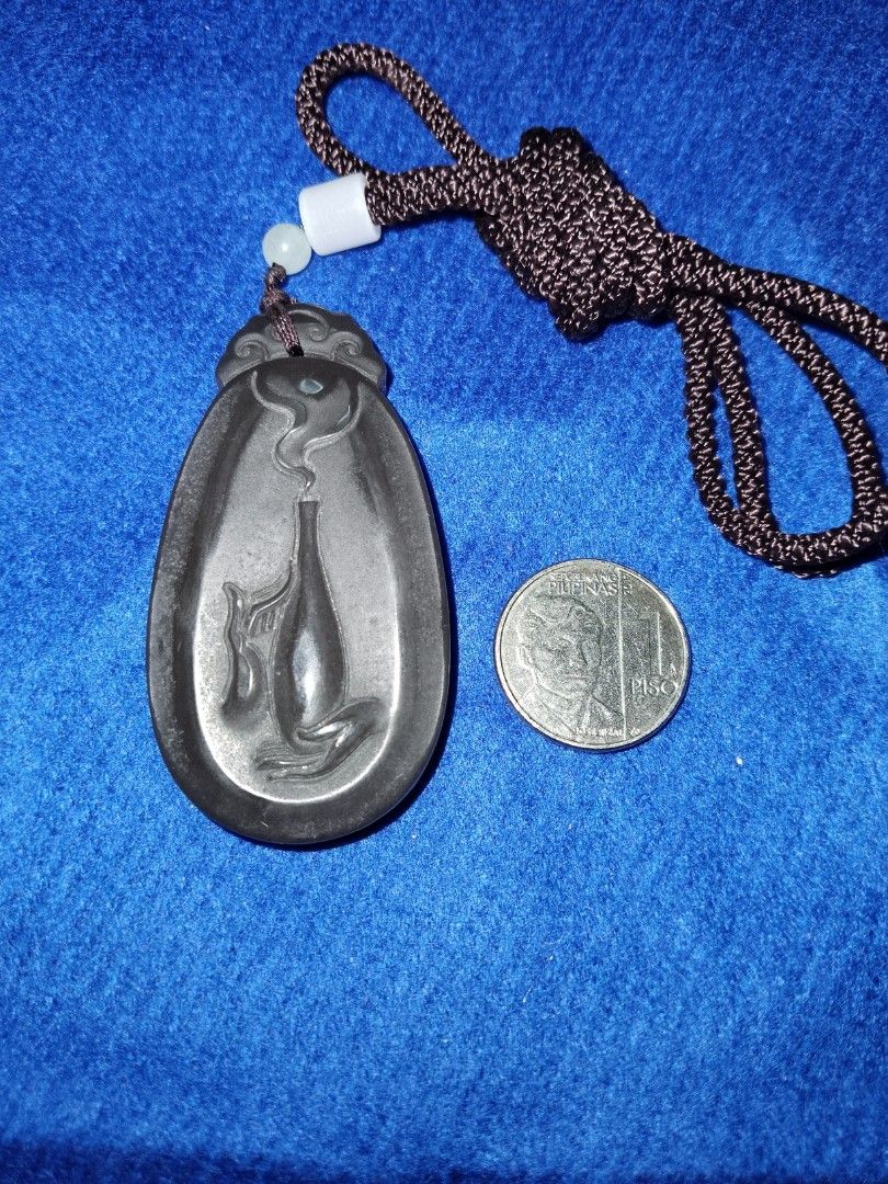 Light brown Jade Pendant with Chinese Characters (Category: Necklaces) located in Dasmarinas. Submitted by 3mi3shop (Listing ID 1416459630, Image 1). Description: Intricate light brown jade pendant with detailed carvings. Features a vase with smoke on one side and Chinese characters on the other. Includes a brown cord. A unique, dark-colored accessory. pymt thru gcash only add'l pymt for shipping fee .