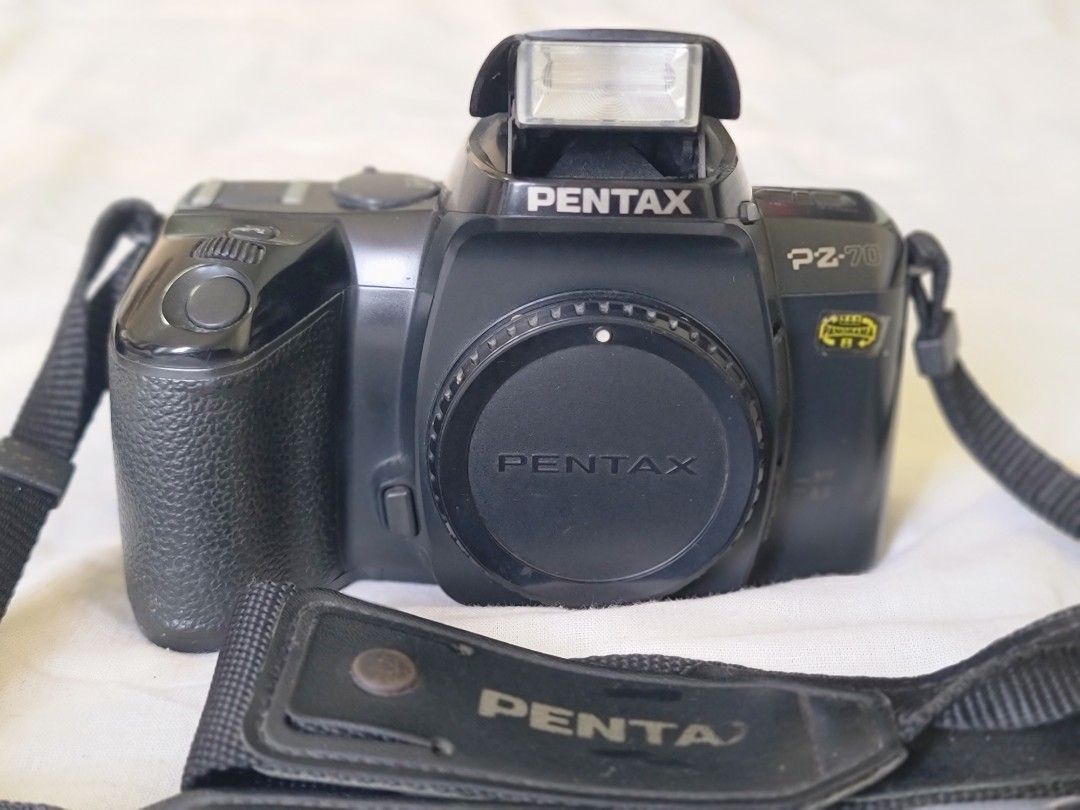 Pentax PZ-70 Camera with Strap (Category: Cameras) located in Manila. Submitted by gane_esla (Listing ID 1416501835, Image 1). Description: FOR COLLECTORS'S USE ONLY. NOT WORKING - Pentax PZ-70 camera - Includes lens cap and neck strap - Built-in flash - Black camera body - Features buttons and dials for settings.