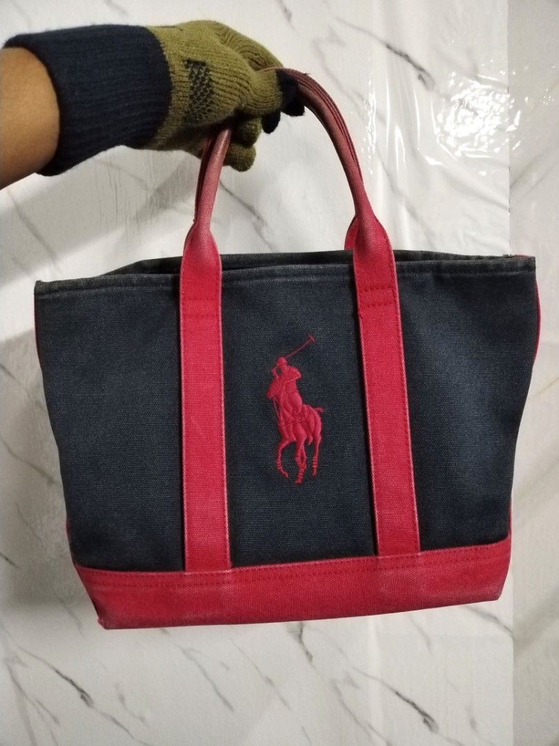 POLO RALPH LAUREN TOTE BAG SZ S (Category: Tote Bags) located in Kuala Terengganu. Submitted by che_man_bundle (Listing ID 1416458740, Image 1). Description: - Navy blue canvas tote bag - Red accents and handles - Polo Ralph Lauren logo on front - Rectangular shape - Interior zippered pocket - Includes a leather label.
