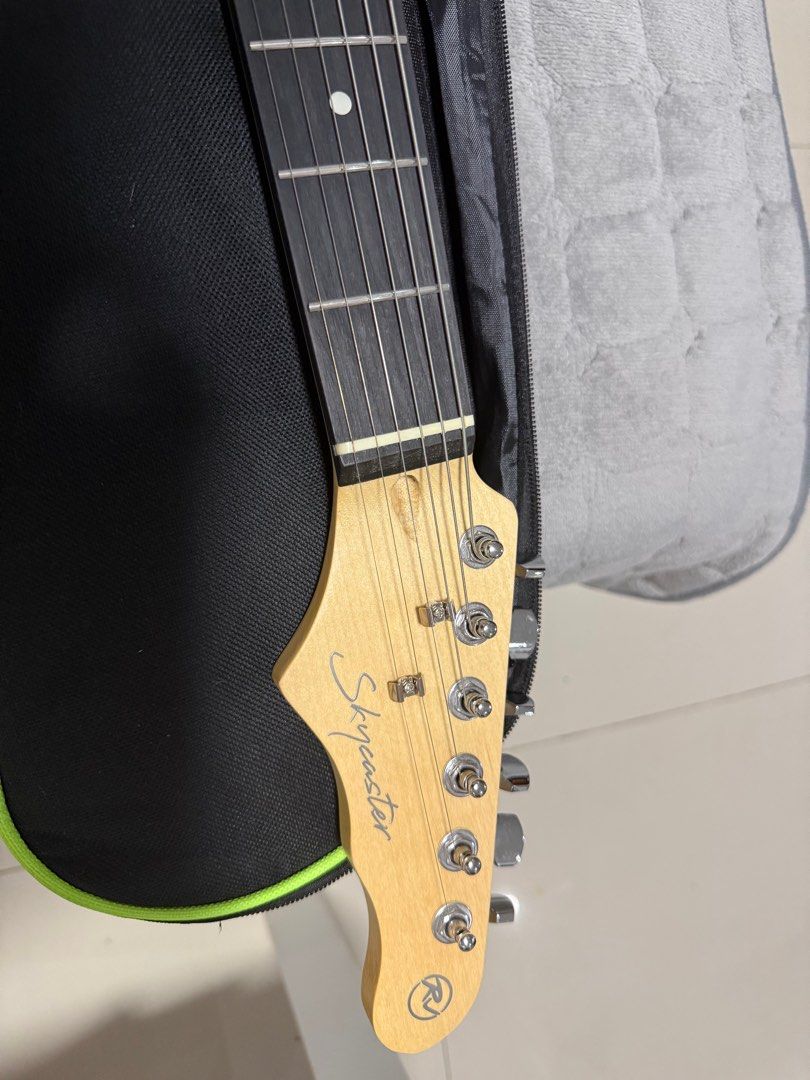 RJ Skycaster Electric Guitar with Case (Category: Musical Instruments) located in Paranaque City. Submitted by spideydream (Listing ID 1416593274, Image 2). Description: - Skycaster electric guitar in black - White pickguard and cream-colored pickups - Maple neck - Tremolo bridge - Volume and tone control knobs - Includes a black carrying case with green trim - Includes a guitar strap - Skycaster logo on headstock.