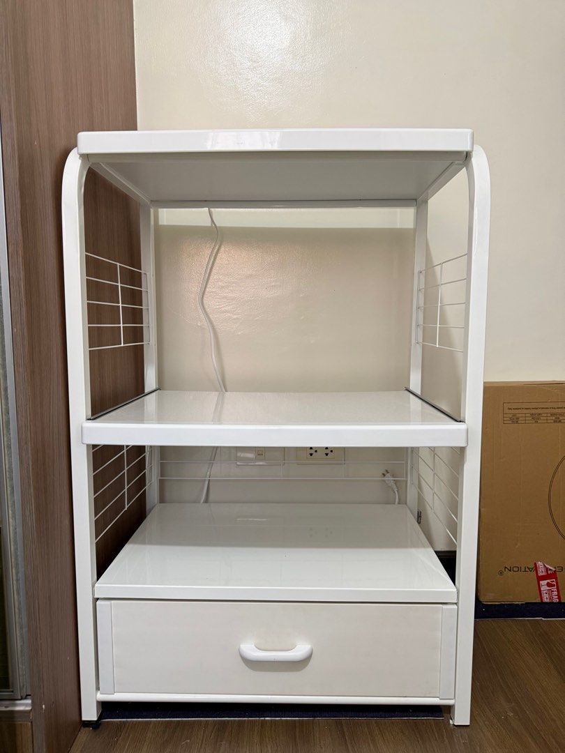White Microwave Oven Rack with Drawer (Category: Ovens & Toasters) located in Taguig. Submitted by lalohan (Listing ID 1416584672, Image 1). Description: - White microwave oven rack - Features a drawer and two shelves - Includes a built-in power outlet - Sturdy metal frame - Wire side panels - Ideal for microwave ovens and other kitchen appliances - Perfect for kitchen use - Measurement: L64 x W42.5 x H109.5 cm Weight: 14.5 kg.