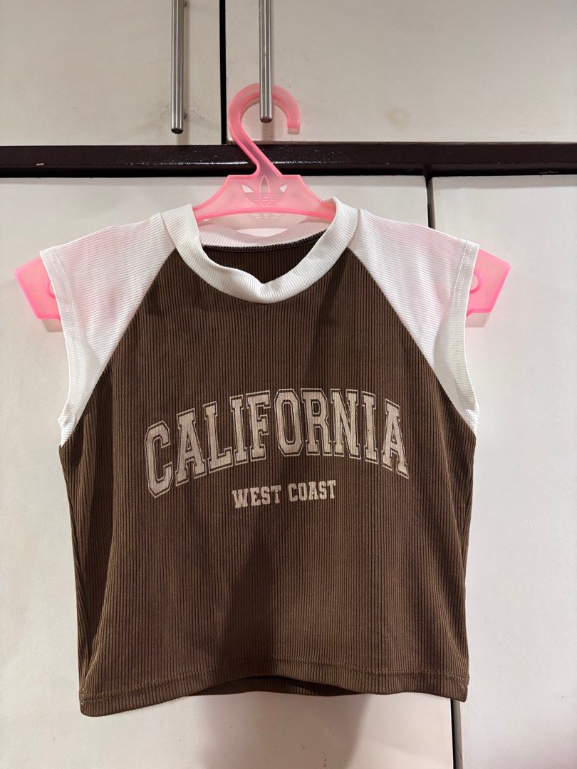 California West Coast Crop Top (Category: Others Tops) located in Manila. Submitted by baddxss (Listing ID 1413166981, Image 1). Description: Brown and white crop top with "CALIFORNIA WEST COAST" printed on the front. Features a ribbed texture on the brown fabric and white panels on the shoulders. Sleeveless design with a round neckline..