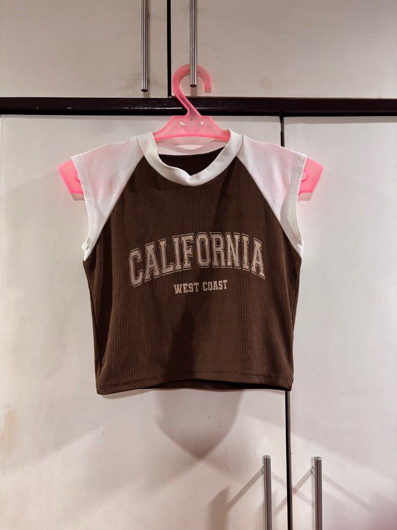 California West Coast Crop Top (Category: Others Tops) located in Manila. Submitted by baddxss (Listing ID 1413166981, Image 3). Description: Brown and white crop top with "CALIFORNIA WEST COAST" printed on the front. Features a ribbed texture on the brown fabric and white panels on the shoulders. Sleeveless design with a round neckline..