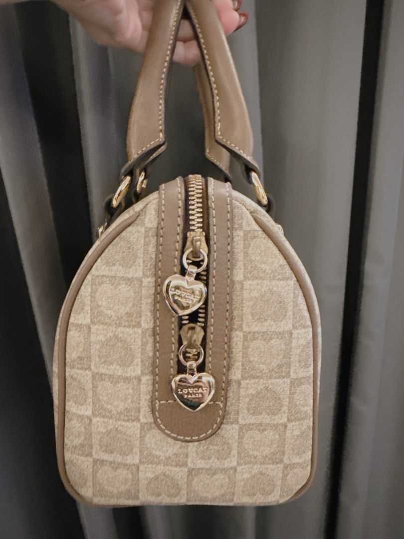 Authentic Loucat Paris Handbag (Category: Luxury Bags & Wallets) located in Lucena. Submitted by fashioncult.ph (Listing ID 1413159766, Image 2). Description: - Loucat Paris handbag - Beige checkered pattern - Top zipper closure with heart-shaped pulls - Two handles - Brown leather accents - Gold-toned hardware - Rectangular shape -L:20 W:25.