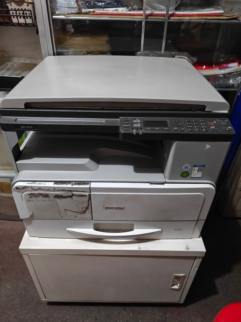 Ricoh Aficio MP 2014 Multifunction Printer (Category: Printers, Scanners & Copiers) located in Manila. Submitted by akintwo023 (Listing ID 1413126221, Image 2). Description: - Ricoh Aficio MP 2014 Multifunction Printer - Scanner and copier functions - Includes paper tray - Features a control panel - Power button and USB port - Flatbed model - Good working condition - Clear photocopy result - Bought Brand-new - Ready to use - included table cabine