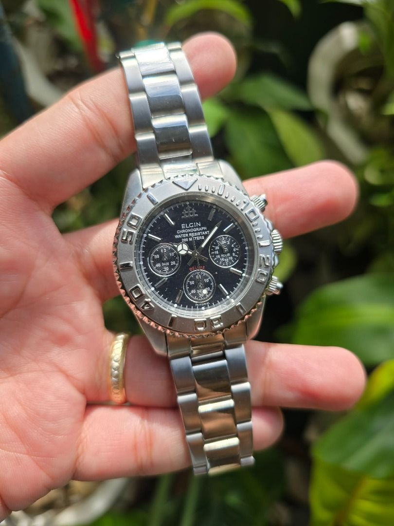 Elgin Chronograph Deluxe model (Category: Men's Watches) located in Manila. Submitted by timearcph (Listing ID 1416785139, Image 2). Description: The watch in the image is an Elgin Chronograph Deluxe model with the reference number FK-1120NGL. It features a black dial with silver-tone case and bracelet, and is designed for water resistance up to 200 meters. Price: 5000 MEETUPS: • Bacoor,Cavite • Las Pinas City SHIPPING: - Open to shipping but buy