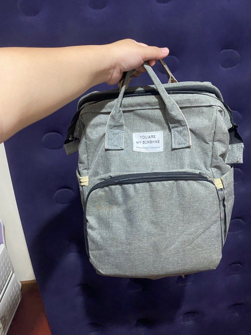 Grey Baby Bag (Category: Diaper Bags & Wetbags) located in Binan City. Submitted by lagunaxpreloved (Listing ID 1416643790, Image 1). Description: - Grey diaper backpack - Multiple compartments and pockets for organization - Top handle and adjustable straps - Front and side pockets - Stroller straps on the back - Features a "YOU ARE MY SUNSHINE" label.