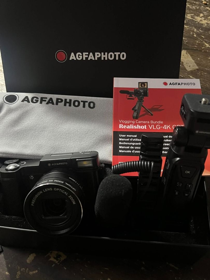 AGFAPHOTO Realishot VLG-4K OPT Digital Camera (Category: Cameras) located in Pasig City. Submitted by jcarevalo (Listing ID 1416927351, Image 1). Description: AGFAPHOTO Realishot VLG-4K OPT digital camera. Includes a microphone, user manual, and other accessories. Features a precision lens with optical zoom. The camera has a built-in flash and a flip-up screen. Comes with a carrying strap and a protective cloth. The camera is black. - BRANDNEW - 