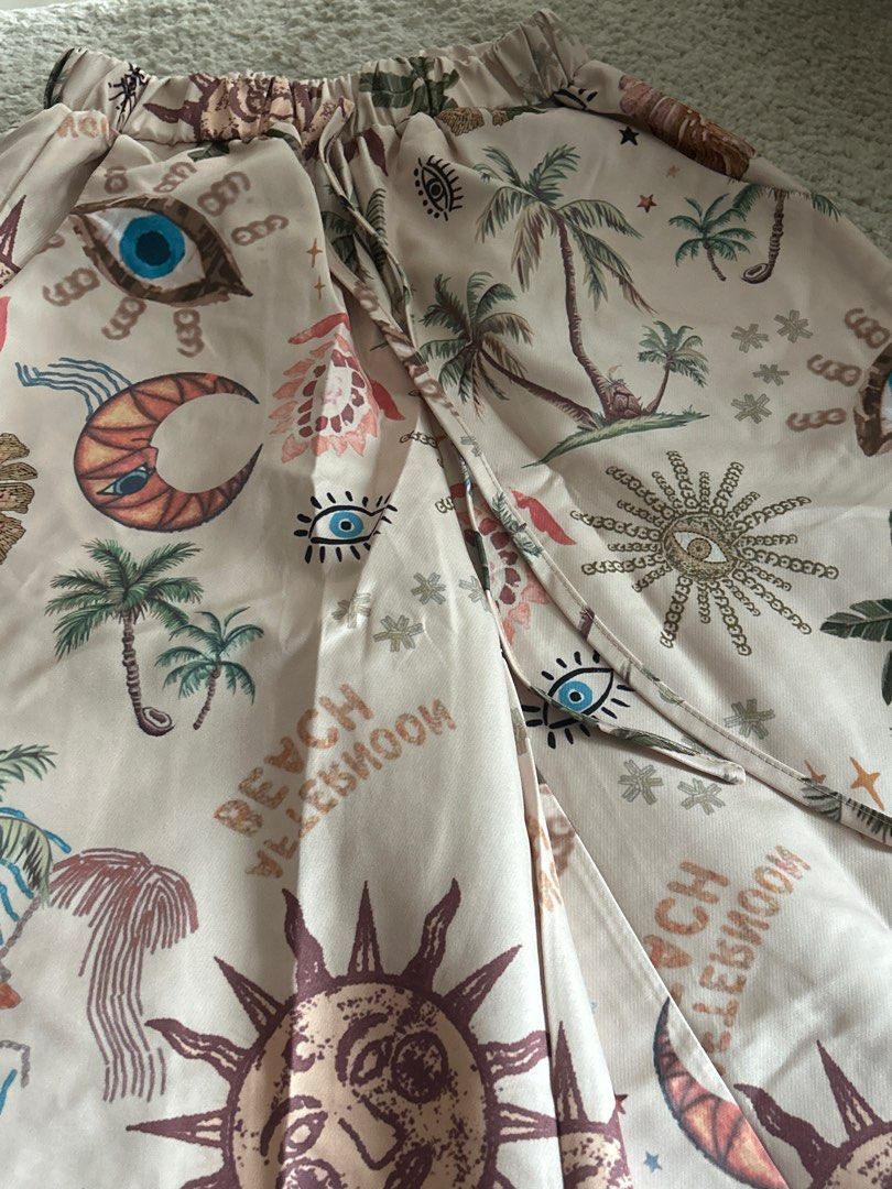 Boho Wide Leg Pants (Category: Other Bottoms) located in Taguig. Submitted by rcdeclutter (Listing ID 1416915022, Image 2). Description: - Wide-leg pants with a unique boho print. - Features suns, moons, eyes, and palm trees. - Elastic waistband with drawstring. - Lightweight and flowy fabric. - Neutral color palette with colorful accents. - Perfect for a relaxed and stylish look..