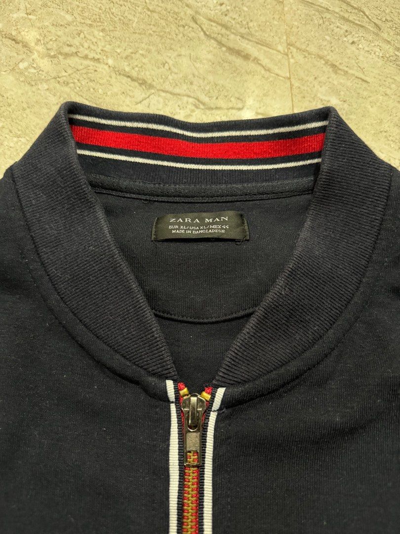 Zara Man Bomber Jacket XL (Category: Coats, Jackets and Outerwear) located in Bacoor. Submitted by 999archives_ (Listing ID 1416859383, Image 2). Description: - Zara Man bomber jacket - Color: Navy blue - Size: XL - Full zip closure - Red, white, and navy stripe details on collar and zip - Made in Bangladesh.