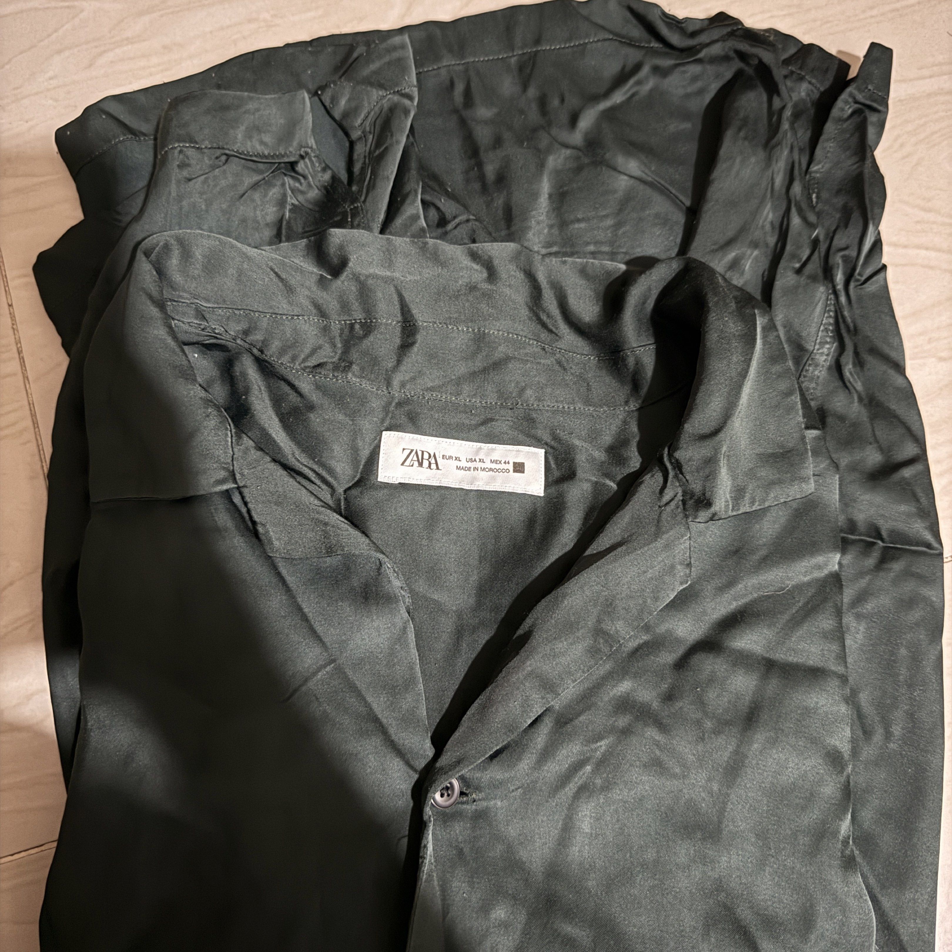 Zara Short Sleeve Button Down Satin Shirt - Green (Category: Shirts) located in Quezon City. Submitted by jajane (Listing ID 1416994884, Image 2). Description: Length 29 Width 25 Issue: lints (bawal sa maselan) - Zara short sleeve shirt - Dark green color - Size: XL - Classic collar - Button-down closure - Silky texture - Made in Morocco - Versatile for various occasions.