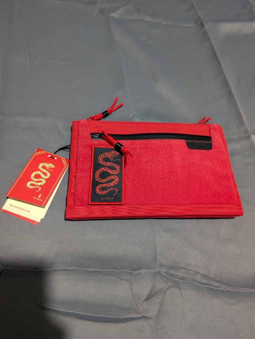 Alpaka Zip Pouch Max - Snake Edition (Category: Belt bags, Clutches and Pouches) located in Quezon City. Submitted by trainforless (Listing ID 1417144236, Image 2). Description: Condition: Never been used Negotiable :) RFS: Decluttering 📦: Lalamove or J&T 💵: GCash, BPI, Seabank Alpaka Zip Pouch Max is a Year of the Snake edition. It features a red exterior with a black zipper and accents. The pouch has multiple compartments inside, including a 