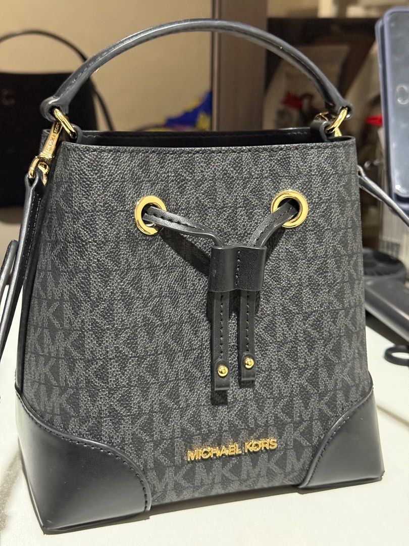 Michael Kors Mercer Small Drawstring Bucket Bag (Category: Luxury Bags & Wallets) located in Dasmarinas. Submitted by jc072727 (Listing ID 1417030598, Image 1). Description: Authentic Michael Kors Mercer bucket bag. Features a drawstring closure, top handle, and a detachable crossbody strap. The bag has a black and gray MK logo pattern with black leather accents. Gold-tone hardware is present on the bag. The tag indicates the model number is 35F2