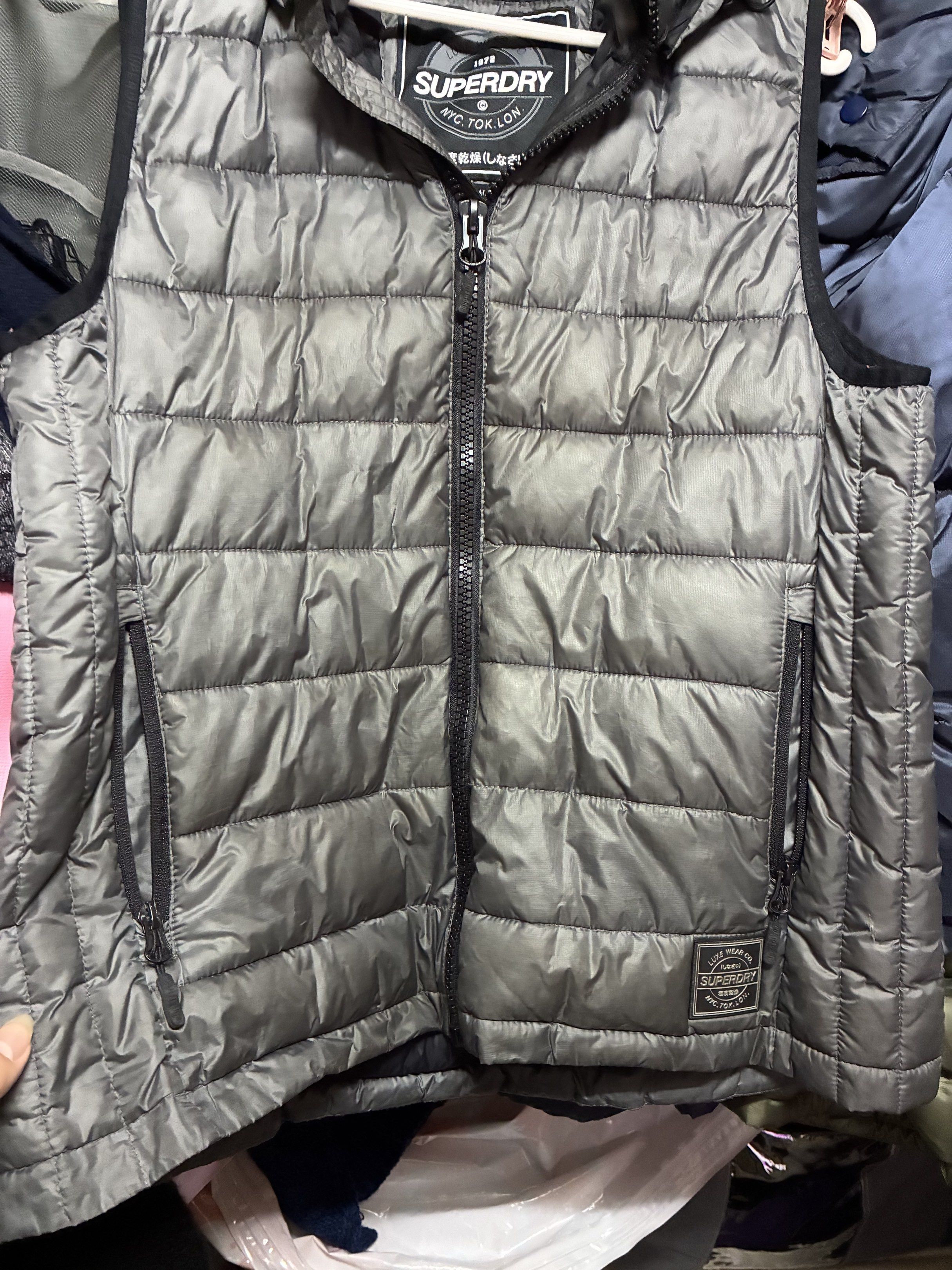 Superdry 夾棉背心 （分類：外套及戶外衣服）位於 Hong Kong。 由 wingbb0123 提交（商品編號 1417043355，圖片 3）。簡介： Superdry 夾棉背心，灰色，有連帽設計。正面有拉鍊和兩個口袋。內襯黑色，有Superdry的標籤。尺寸為XL。背心填充物蓬鬆，適合日常穿著。九成新。。